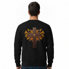 A man viewed from behind wearing a black crewneck sweatshirt with a large graphic on the back featuring a brown cross overlaid with golden-brown autumn leaves.