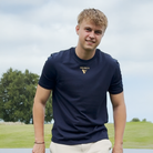 Person wearing a visudeco navy blue t-shirt with logo on the front - outdoors on a grassy area.