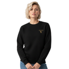 Woman wearing a black sweatshirt with a golden logo in front.