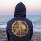 Person wearing a hoodie with a peace symbol design on a beach