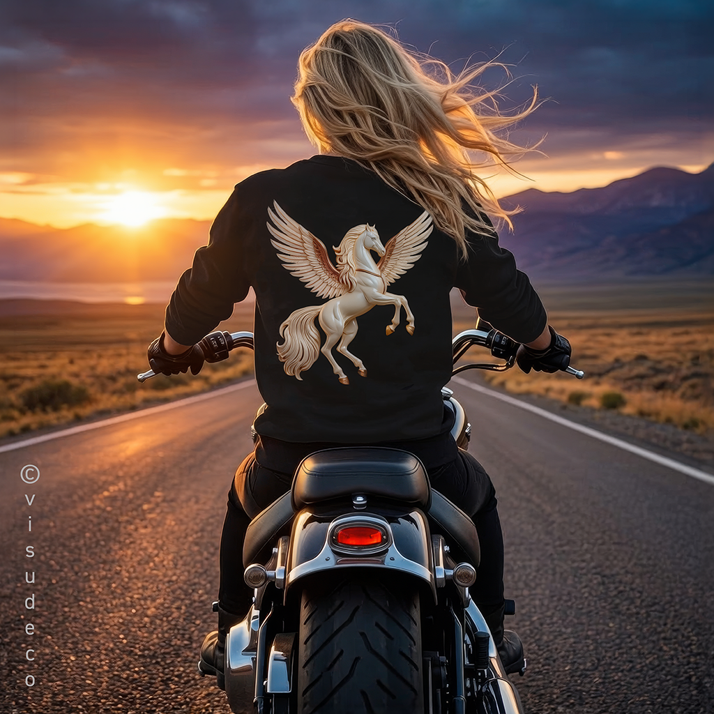 A woman riding a motorcycle on a road at sunset, viewed from behind. She wears a black sweatshirt with a large white winged horse graphic on the back.